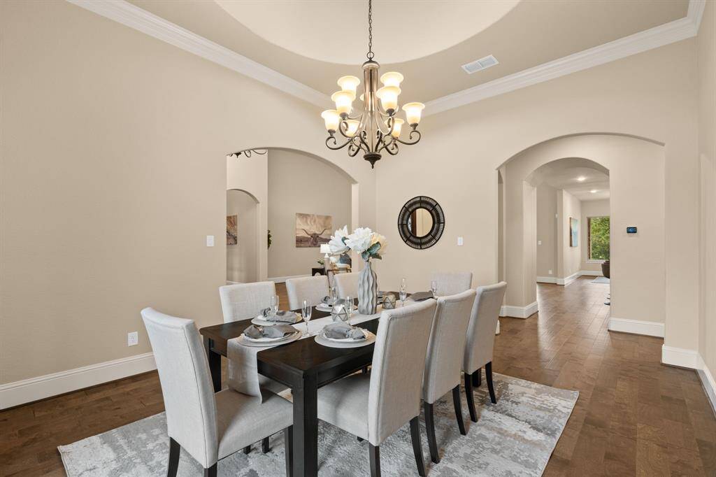The formal dining room offers a seamless flow into the heart of the home, with engineered wood flooring, elegant crown molding, and a soaring rotunda ceiling with a statement chandelier. It’s the perfect setting for everything from casual dinners to grand celebrations.
