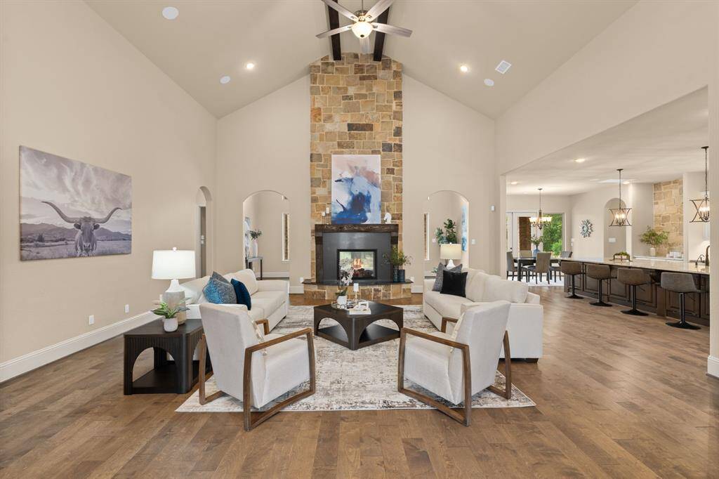 This stunning family room is the perfect blend of comfort and sophistication, featuring a soaring 20’ cathedral ceiling with exposed wood beams and a striking two-sided stone fireplace. The open-concept design flows effortlessly into the kitchen and dining areas, creating a seamless space for both upscale entertaining and everyday living.