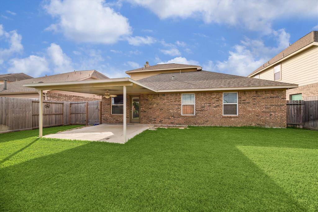 Step into the fully fenced backyard featuring a covered porch – perfect for barbecues, outdoor lounging, or a quiet evening in the fresh air of Tomball, TX.