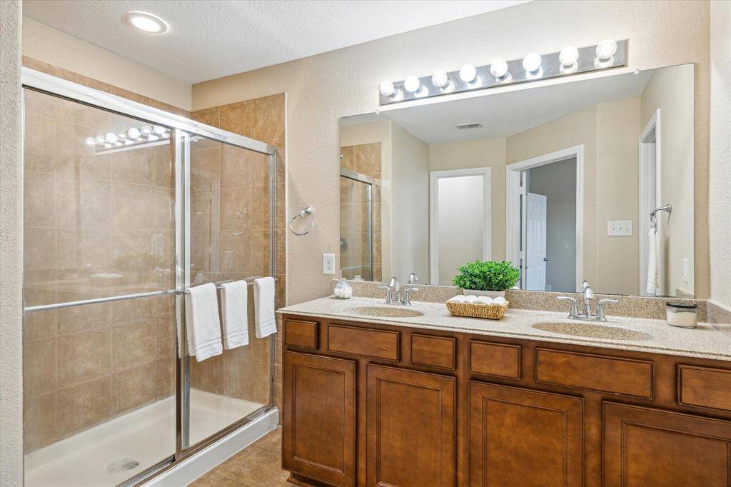 En-suite bathroom with dual vanities, walk-in shower, and walk-in closet