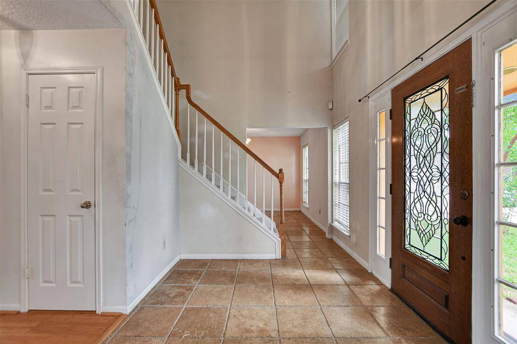 This nice inviting 2-story foyer features a leaded glass door with side lights that provide tons of natural light. Tile flooring makes cleanup easy after bad weather days.