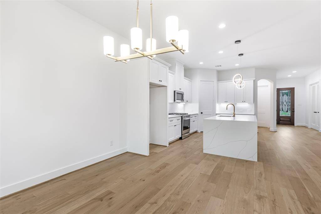 The open layout features hardwood floors and contemporary lighting fixtures, offering a fresh and inviting space for cooking and entertaining.