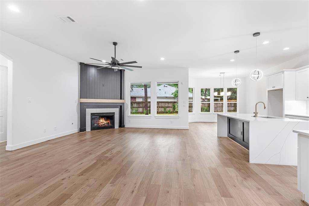 This spacious open-concept living area features hardwood floors, a modern fireplace, and ample natural light from large windows.