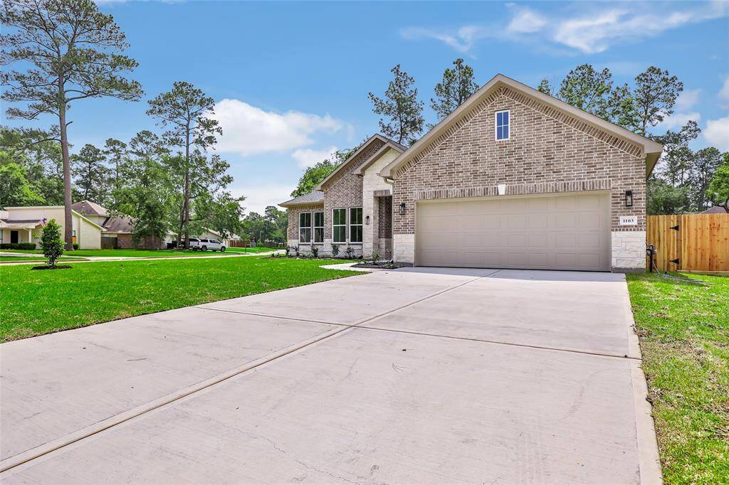 This photo showcases a modern brick home with a spacious driveway and two-car garage. The property features a well-maintained lawn and is set in a neighborhood with mature trees, providing a serene and inviting atmosphere.