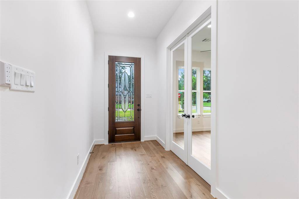 This photo shows a bright entryway with a decorative glass front door and wood flooring.
