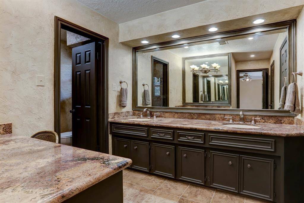 Primary bathroom on suite with granite countertops, double sinks and updated faucets