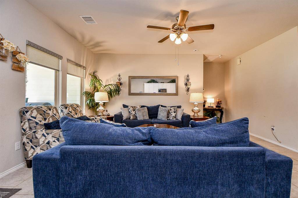 Spacious living room with neutral walls and tile flooring, large windows allow natural light and decorative elements add warmth.