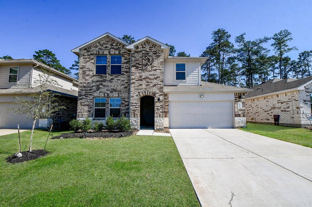 The house features a welcoming entrance with well-maintained landscaping with a backdrop of tall trees.