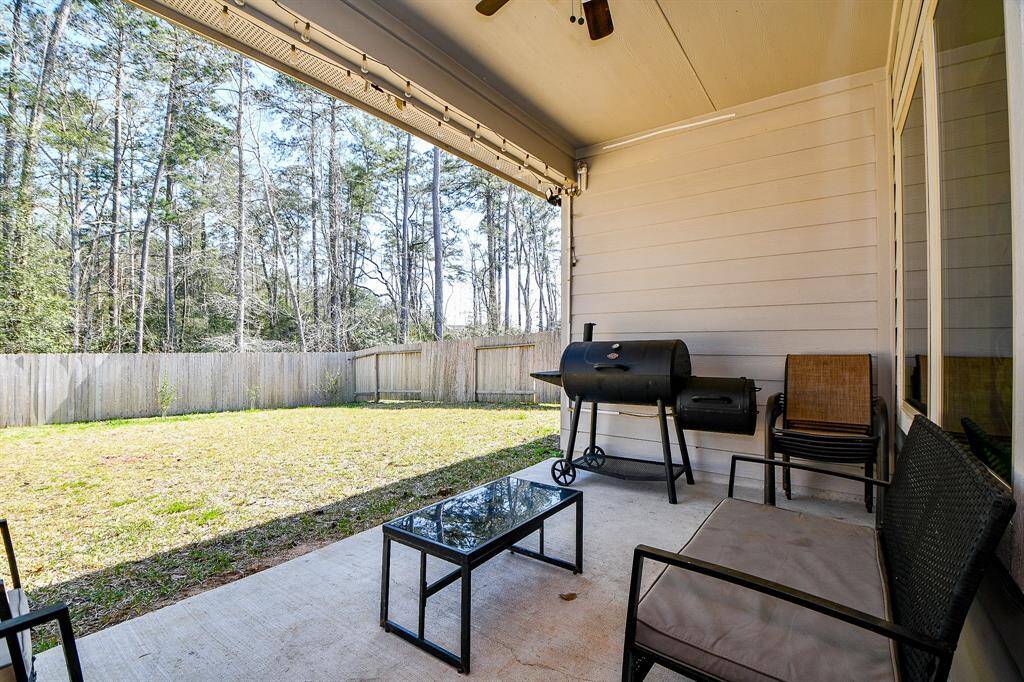 A cozy covered patio spacious fenced backyard bordered by tall trees offering privacy and a serene outdoor space for relaxation or entertaining.