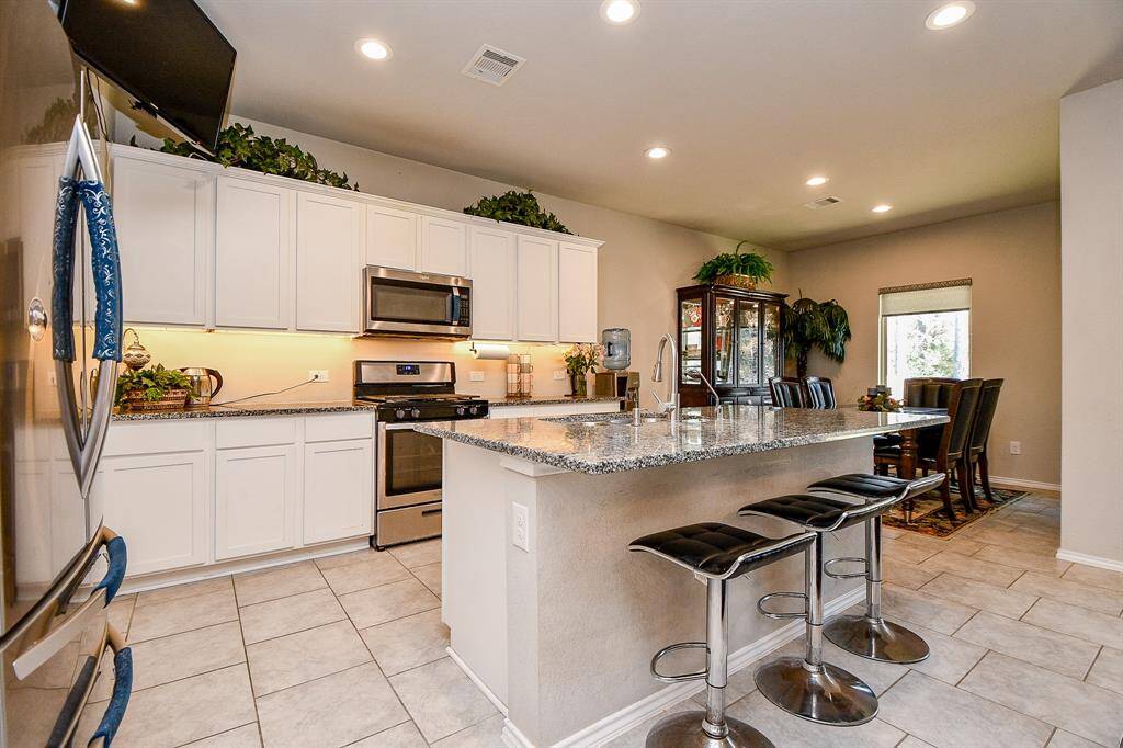 Spacious granite island with bar seating. It flows into a dining area with natural light, creating an inviting space for cooking and entertaining.