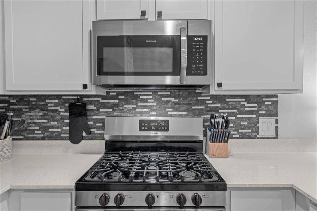 In the kitchen alone, the style boasts modern features, including sleek quartz countertops, crisp white cabinets, and stainless steel appliances. A beautiful tile backsplash adds texture and visual interest, tying the whole space together with a clean, contemporary feel.