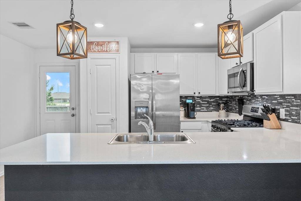 This kitchen is small yet thoughtfully designed, offering a surprisingly spacious feel thanks to its efficient layout and generous quartz countertops. Crisp white cabinets add a clean, modern touch, while sleek stainless steel appliances provide a stylish and functional complement.
