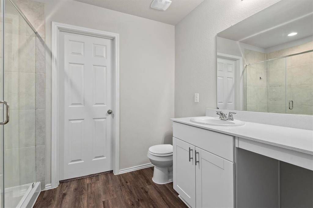 The primary bathroom features a spacious white vanity with plenty of counter space, creating a fresh and airy feel throughout. The all-white palette adds a crisp, clean look that’s both timeless and serene.