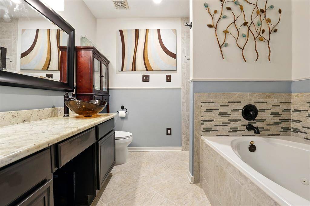 Stunning updated primary bathroom featuring modern finishes, a walk-in shower, tub and a stylish vanity.
