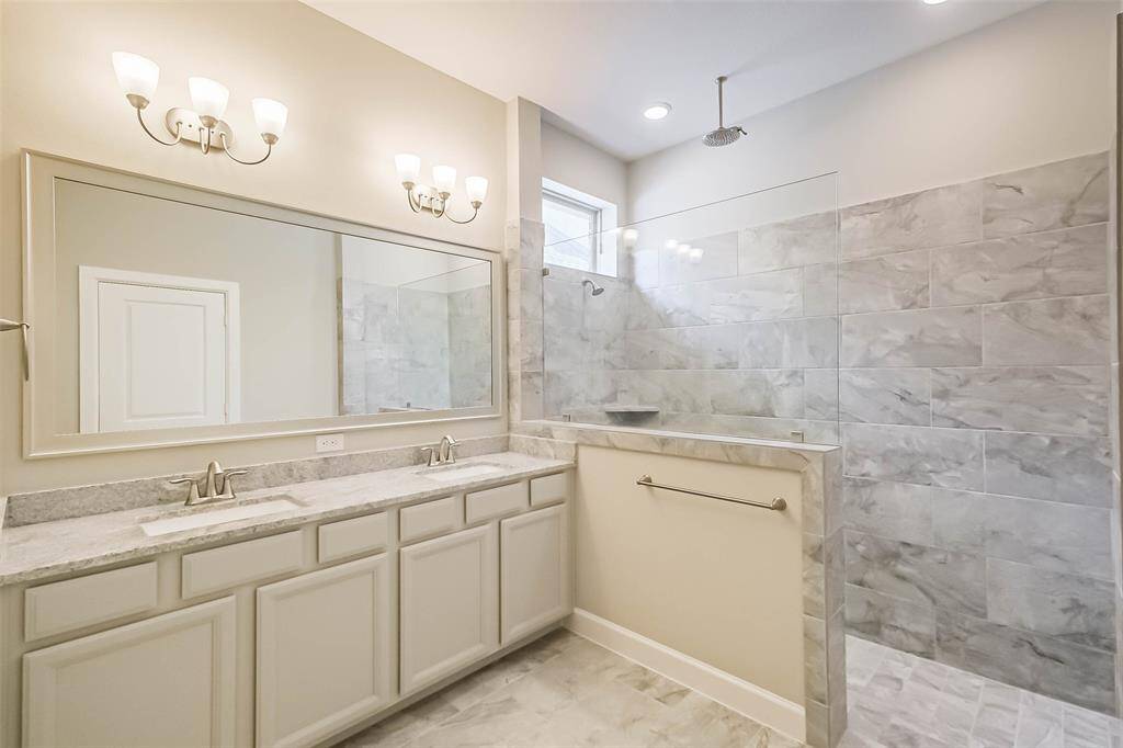 Elegant framed mirror, dual vanity sinks, spacious walk-in shower with high ceilings and a secondary rain shower head above. Your retreat awaits!