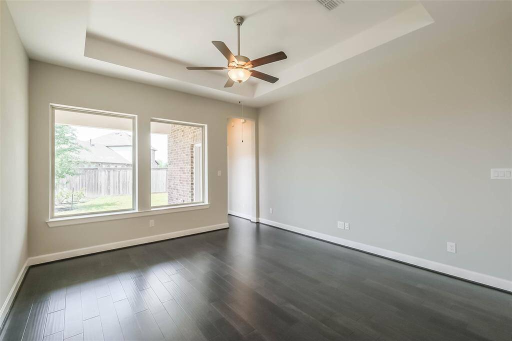 Another view of the living area featuring tray ceiling, and energy efficient ceiling fan.