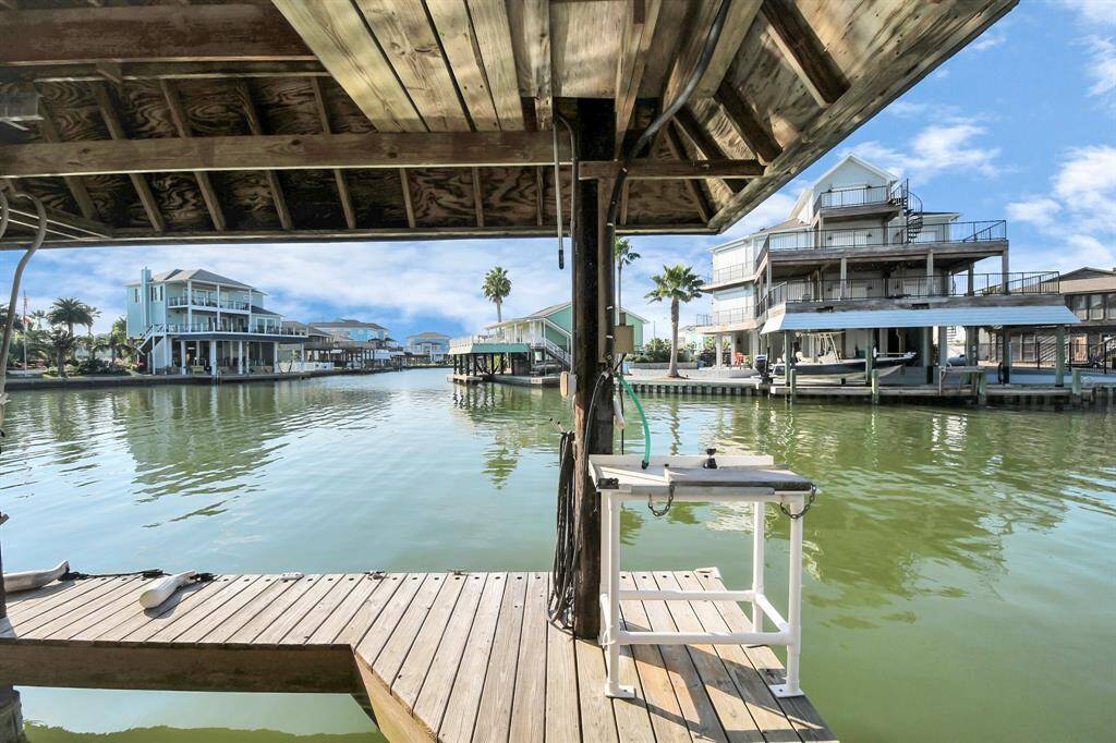 Waterfront view with a wooden dock, overlooking a calm canal lined with homes and palm trees. Ideal for boating and enjoying serene waterside living.