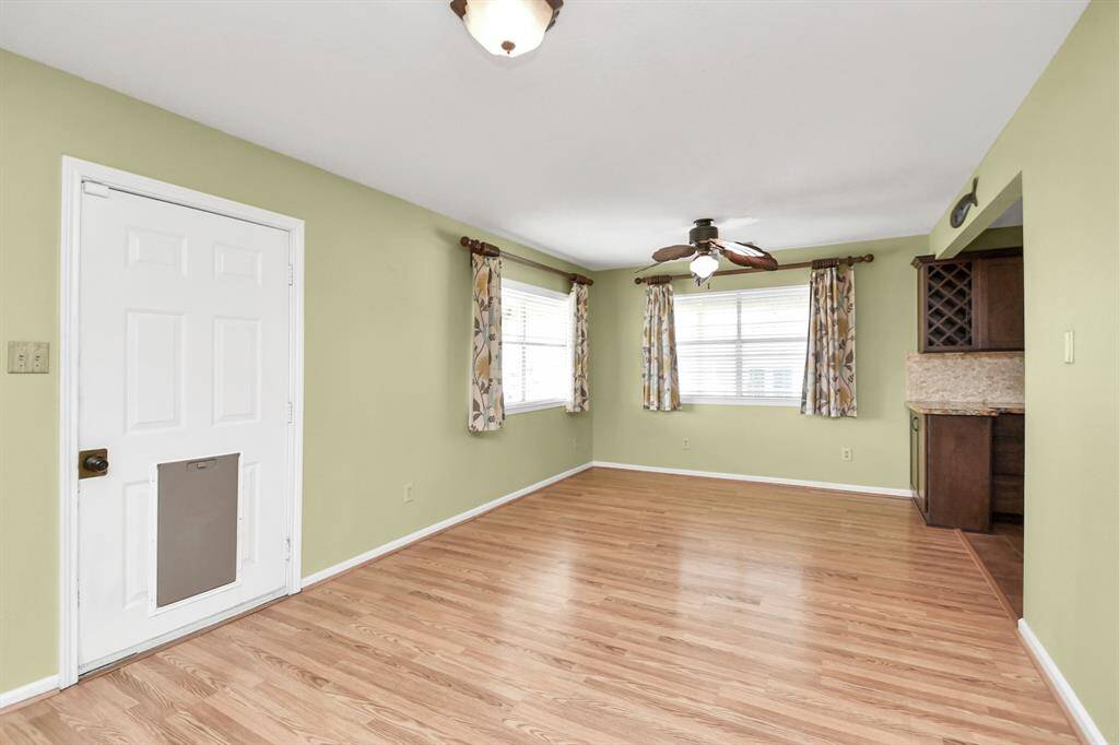 Bright dining area with laminate floors, ample natural light, and a ceiling fan, perfect for gatherings.