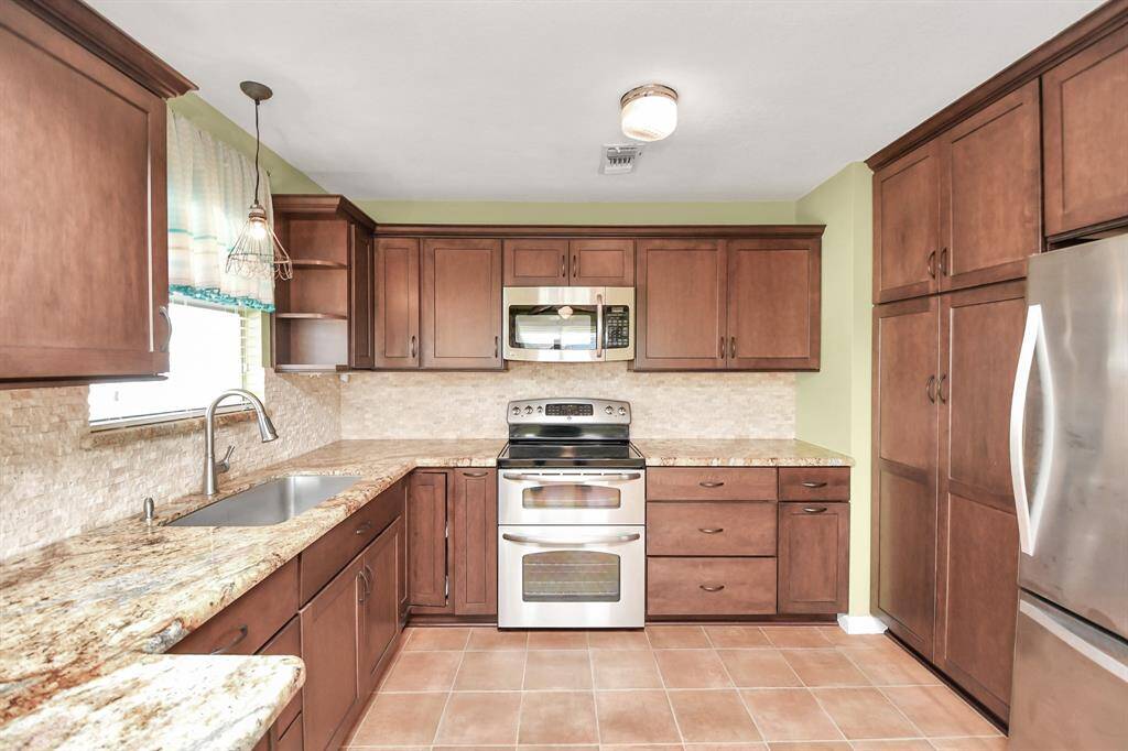 This kitchen features warm wood cabinetry, stainless steel appliances, and granite countertops. It offers ample storage space and a cozy, inviting atmosphere.