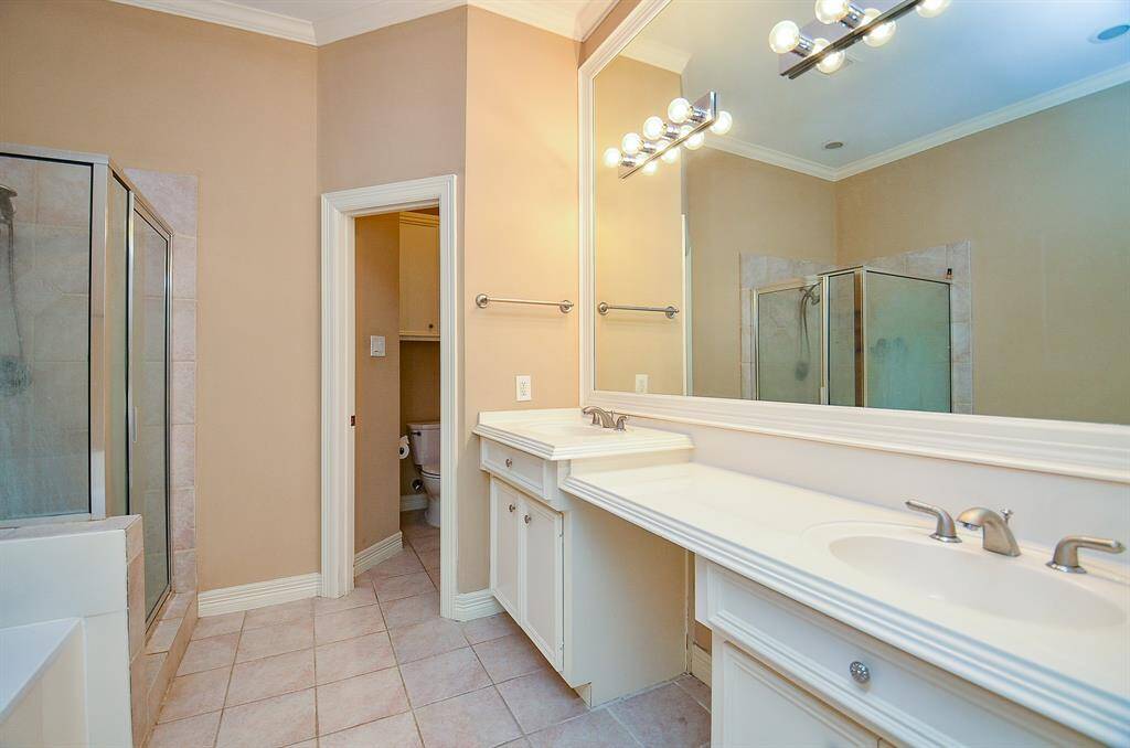 Your primary ensuite bath shines with wall-wide mirrors and trim lighting above dual sinks/vanity, with tub and separate walk-in shower, opposite.
