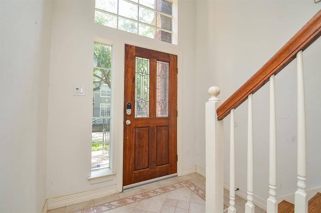 This is a view of the bright entry, from the inside, with pale walls and tile flooring. The home offers 3 bedrooms (each with its own ensuite bath) and a half-bath, gracing a 1,728 square-foot lot with 2,812 square-feet of interior living space.
