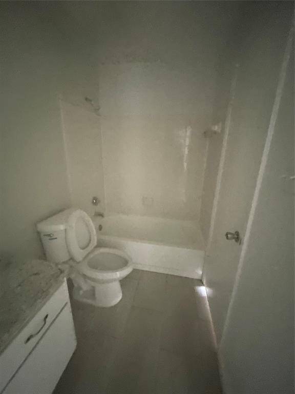 A compact bathroom featuring a bathtub-shower combo, toilet, and a vanity with storage. The space is simple with neutral tones, offering a clean slate for personalization.