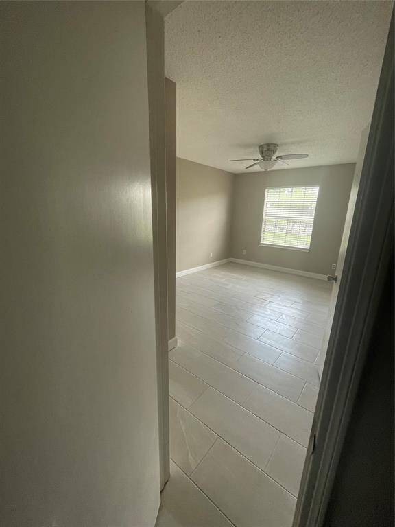 Bright, neutral-toned room with tile flooring, ceiling fan, and a window providing natural light.