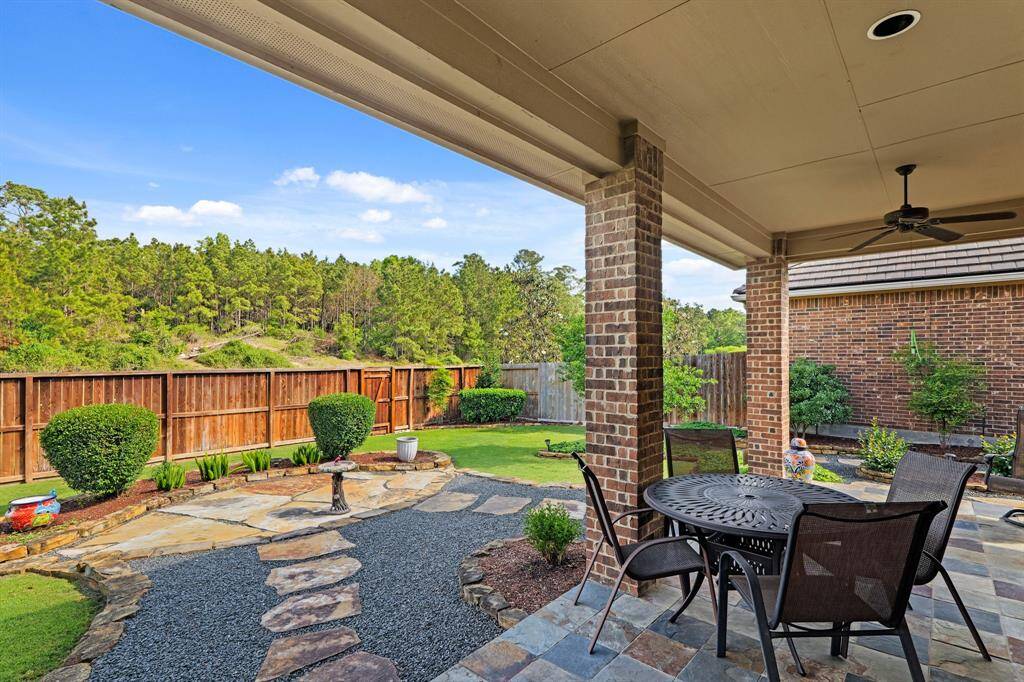 Gorgeous covered patio with a great view and no neighbors behind. Unique raised area of a small hill with lots of trees. Patio has brick columns and tiled floor. Yard is designed with pathways, flower beds and beautiful rock combinations with flagstones.