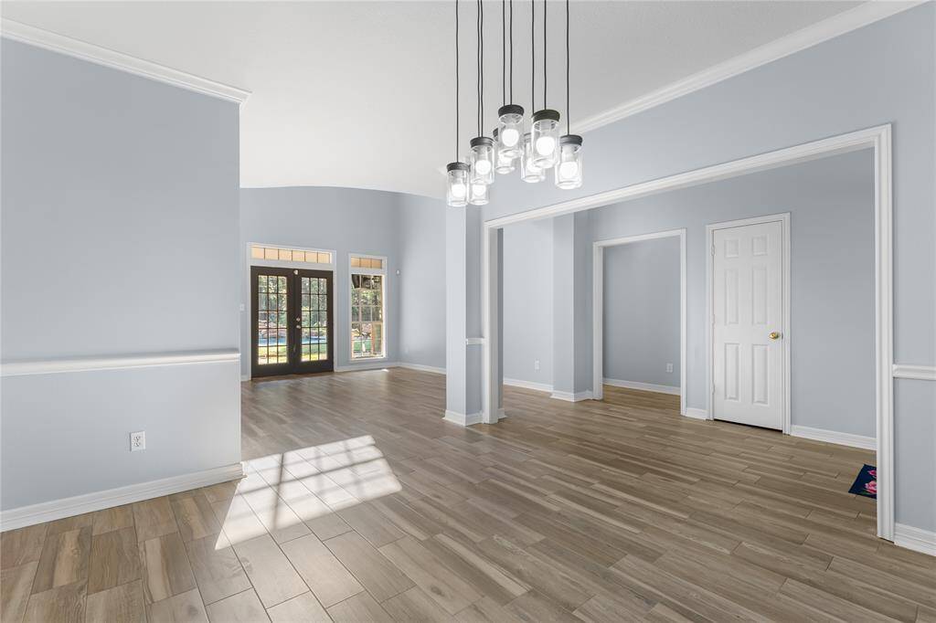 Dining room open to formal living & kitchen with updated lighting.  Ample natural light from French doors leading outside, and multiple entryways for easy access to adjacent rooms.