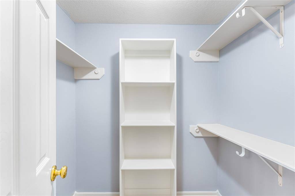 Walk in primary closet space featuring built-in shelves and tons of storage!