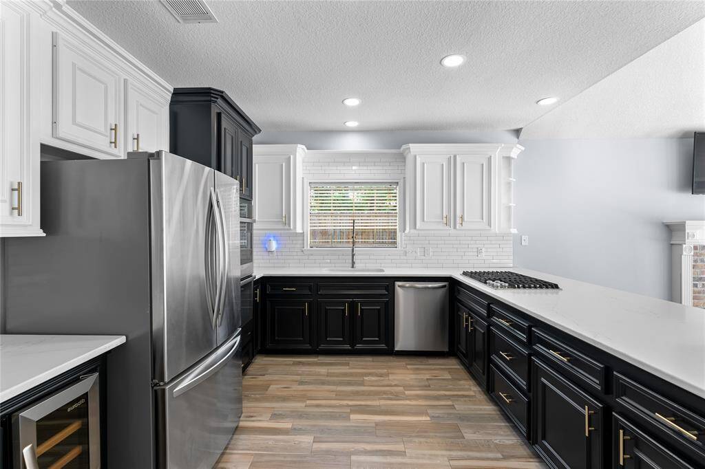 Subway tile backsplash, and recessed lighting. The room features wood flooring and gas cooktop.