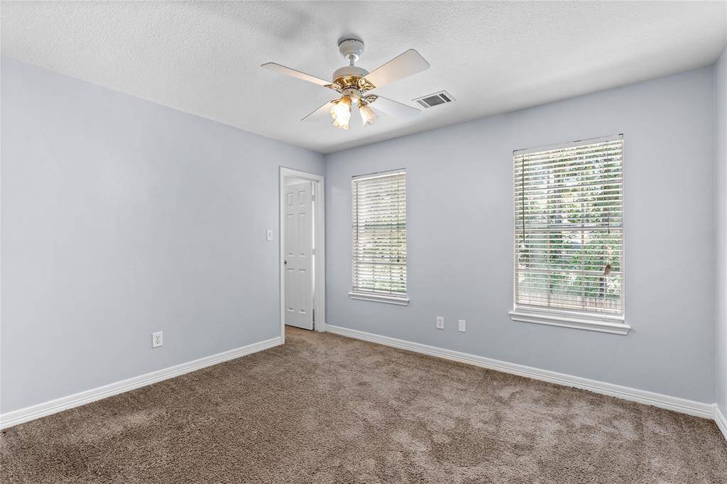 Secondary bedroom located upstairs features two windows with blinds, providing natural light, and a ceiling fan.
