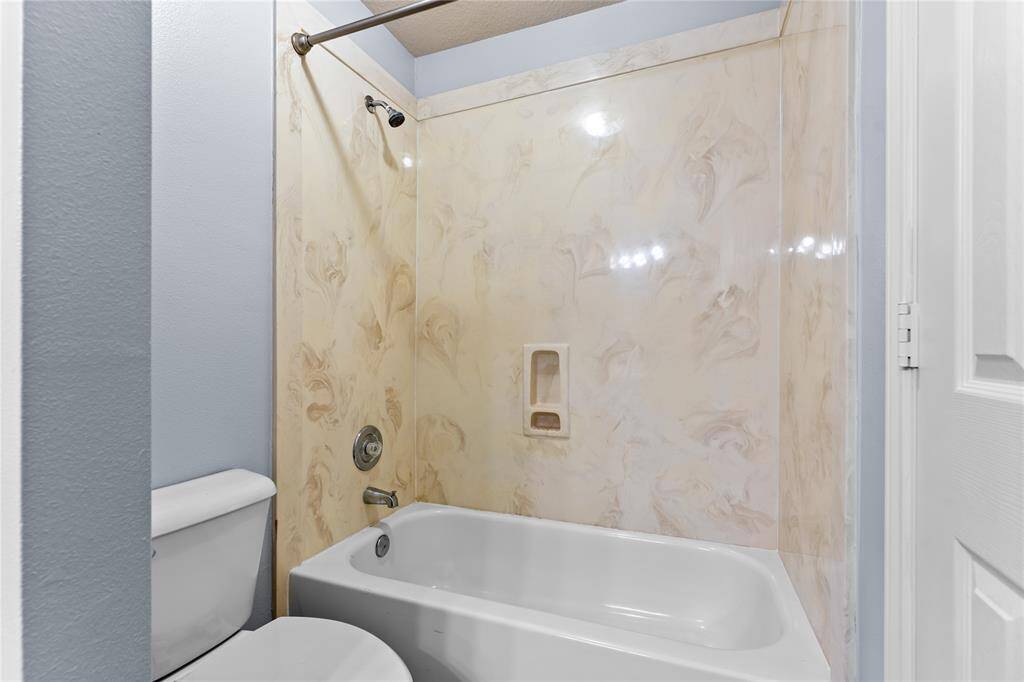 Secondary bath upstairs has marble-like surround tub with shower.