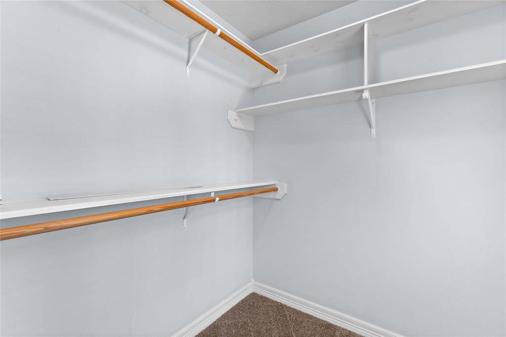 Secondary bedroom walk-in closet with plenty of shelving and hanging rods.