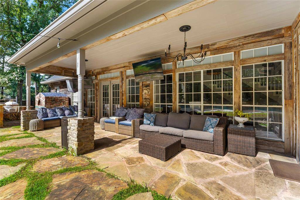 Covered back patio featuring comfortable seating with upgraded lighting, TV and large windows. This space is ideal for relaxing or entertaining outdoors.