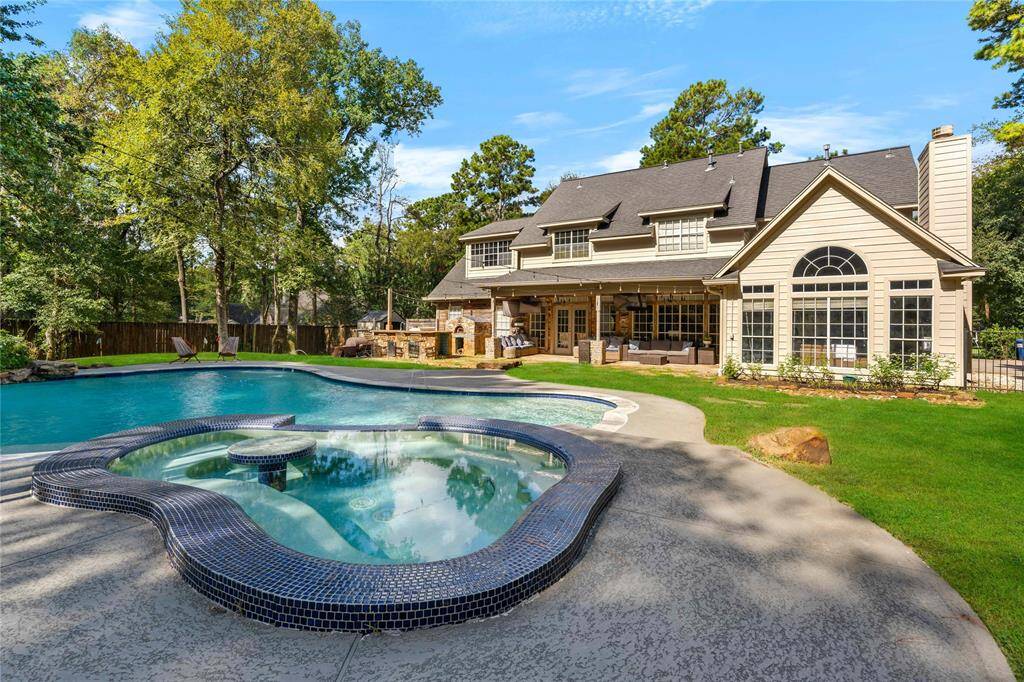 Serene backyard is perfect for entertaining or relaxing with a large pool and spa (with table!), surrounded by mature trees. The house has multiple windows for natural light and a cozy covered porch area.