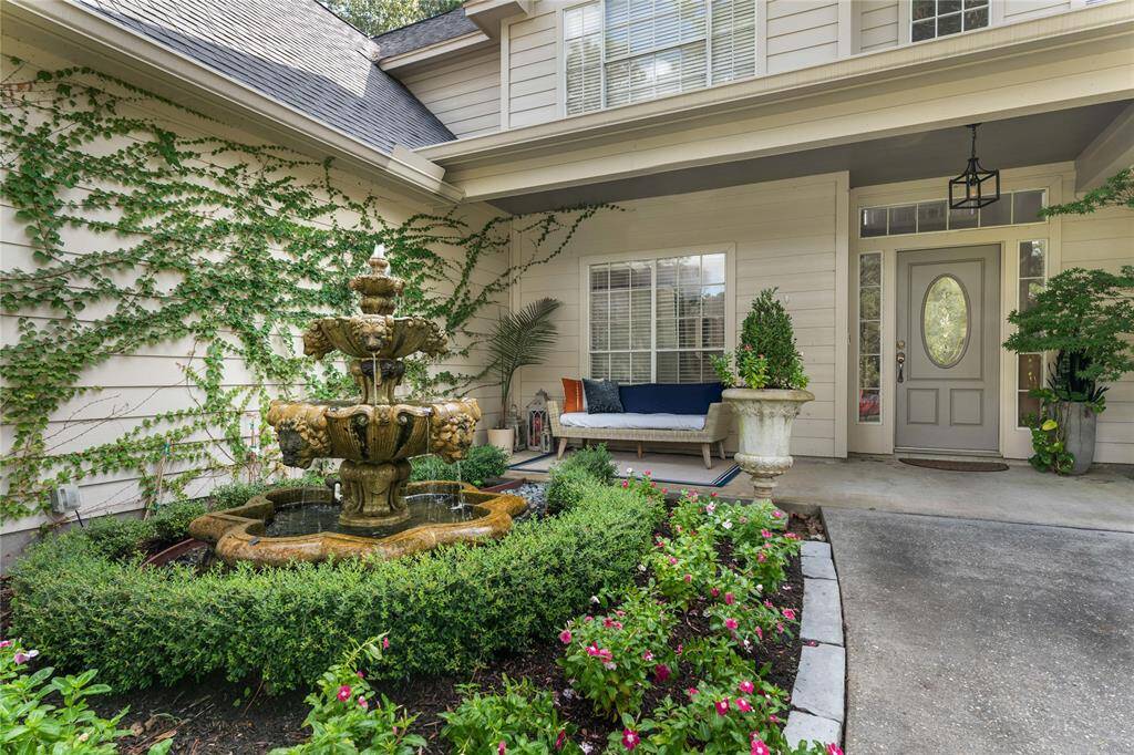 Stunning entryway featuring an ornate fountain, lush greenery, and a cozy sitting area, creating a warm welcome to this inviting home.