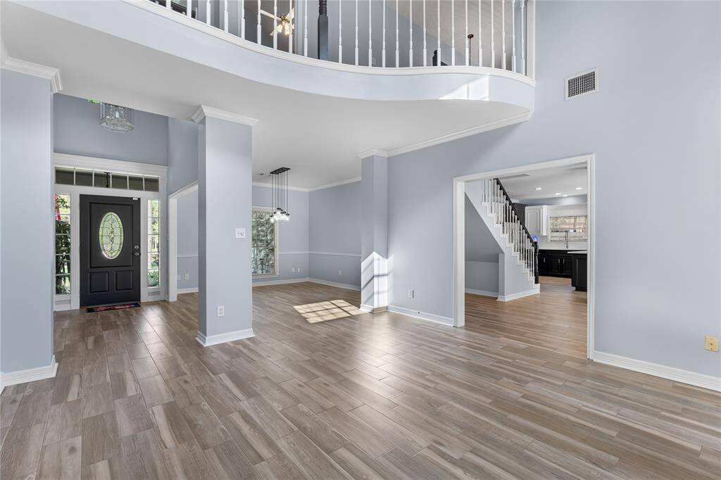 Entry with open floor plan, high ceilings, featuring a curved staircase, light wood floors, and a neutral color palette. Recent paint throughout!