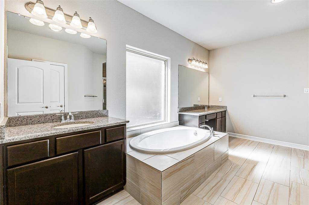 Luxuriate in the spa-like primary bathroom featuring dual vanities, a soaking tub, and granite countertops. A perfect blend of functionality and relaxation awaits.