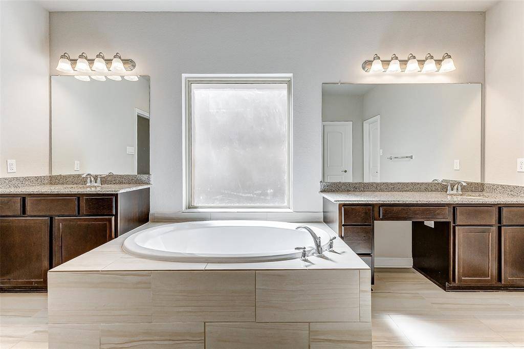 The primary bathroom’s expansive dual vanities make getting ready a breeze. Elegant lighting and plenty of counter space add to its upscale appeal.
