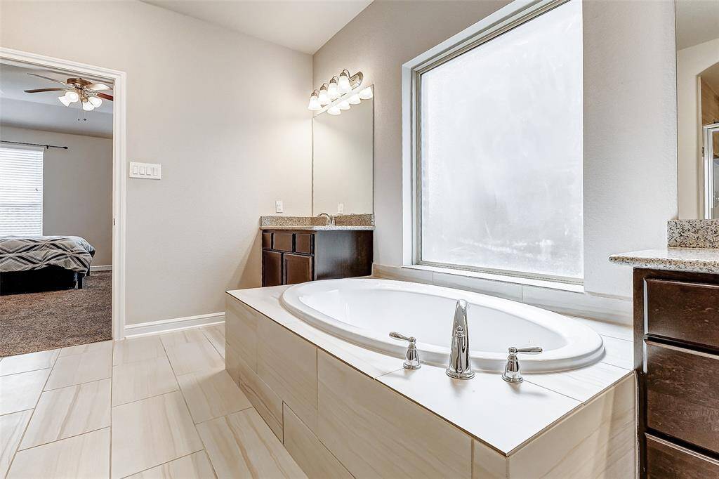 Soak away your worries in this luxurious garden tub, beautifully set with a large frosted window allowing soft natural light while preserving privacy. The ample granite counter space and dual vanities add convenience and style, making it an ideal spa-like retreat just steps away from the primary bedroom.