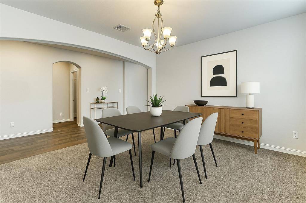 This stunning formal dining area offers a refined blend of comfort and sophistication. Bathed in natural light from triple front-facing windows, the space features a modern chandelier and a soft neutral palette that enhances its open, welcoming feel. Elegant wood-look tile transitions to plush carpet under a chic area rug, creating a perfect setting for hosting intimate dinners or festive celebrations. A graceful entryway leads seamlessly into this stylish, light-filled room.