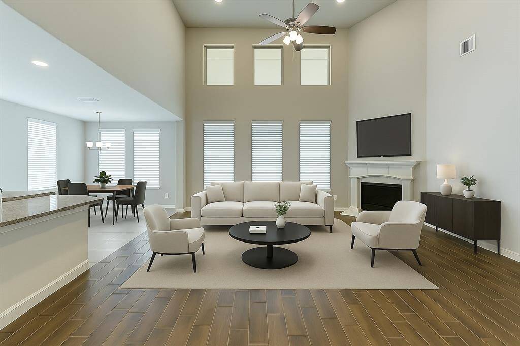 his open-concept layout effortlessly combines the kitchen, dining, and living spaces, ideal for entertaining or enjoying family time. The grand ceilings and natural light streaming in create an airy atmosphere, complemented by the fireplace and modern finishes throughout.