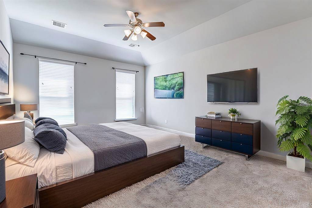 A spacious retreat with plush carpeting, large windows for natural light, and high ceilings. The primary bedroom provides a serene space to relax and recharge.