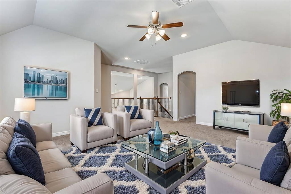 Bright and spacious, this upper living area offers endless possibilities—whether as a cozy family lounge, a game room, or a home office. The soft carpeting provides comfort underfoot, while the ceiling fan and recessed lighting add ambiance to the open design. Overlooking the staircase with stylish iron railings, this loft connects seamlessly to the rest of the home, providing both a private retreat and a social hub for gatherings.