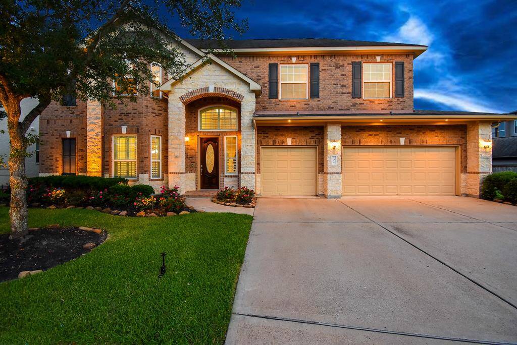 Gorgeous home with 3 car garage, stone & brick construction. Sunset photo to show the decorative landscape lighting.