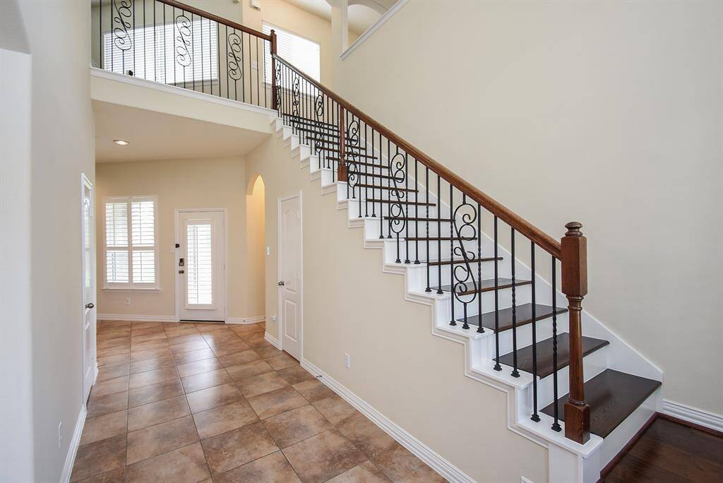 Beautiful staircase with decorative wrought iron spindles and wood bannisters.