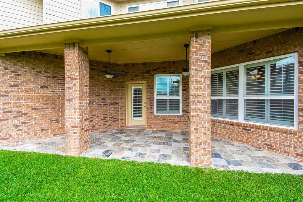 Another view of the large, covered patio with slate floors & ceiling fans.