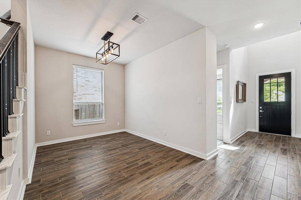 The open formal dining room is illuminated with natural light and a sleek, modern light fixture.