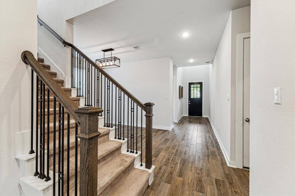 As you enter the home through the bright entryway with high ceilings and a modern light fixture, your attention is drawn to the open staircase with sleek railings & iron balusters, leading to the upper level.
